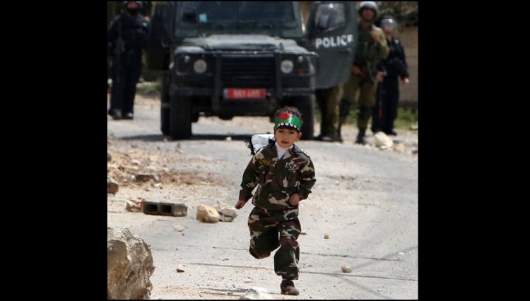 Bocah yang berseragam ala tentara ini lari usai melemparkan batu ke arah polisi Israel